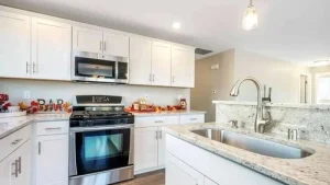 A kitchen with white cabinets , stainless steel appliances , granite counter tops and a sink.