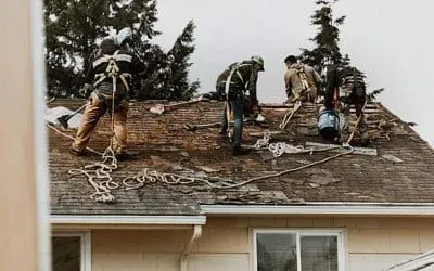 A group of men are working on the roof of a house.