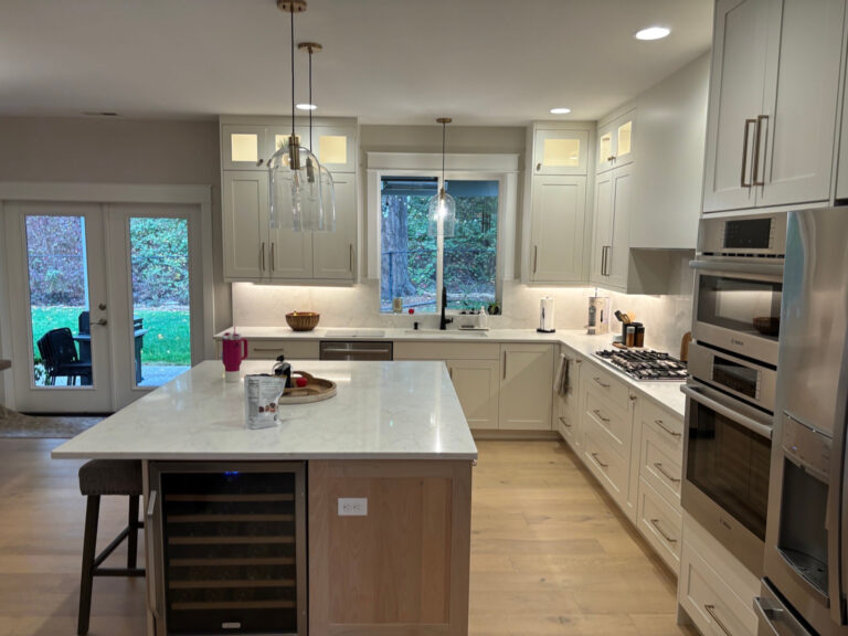 Kitchen with white cabinets, a wood-finish island, pendant lights, and stainless steel appliances.
